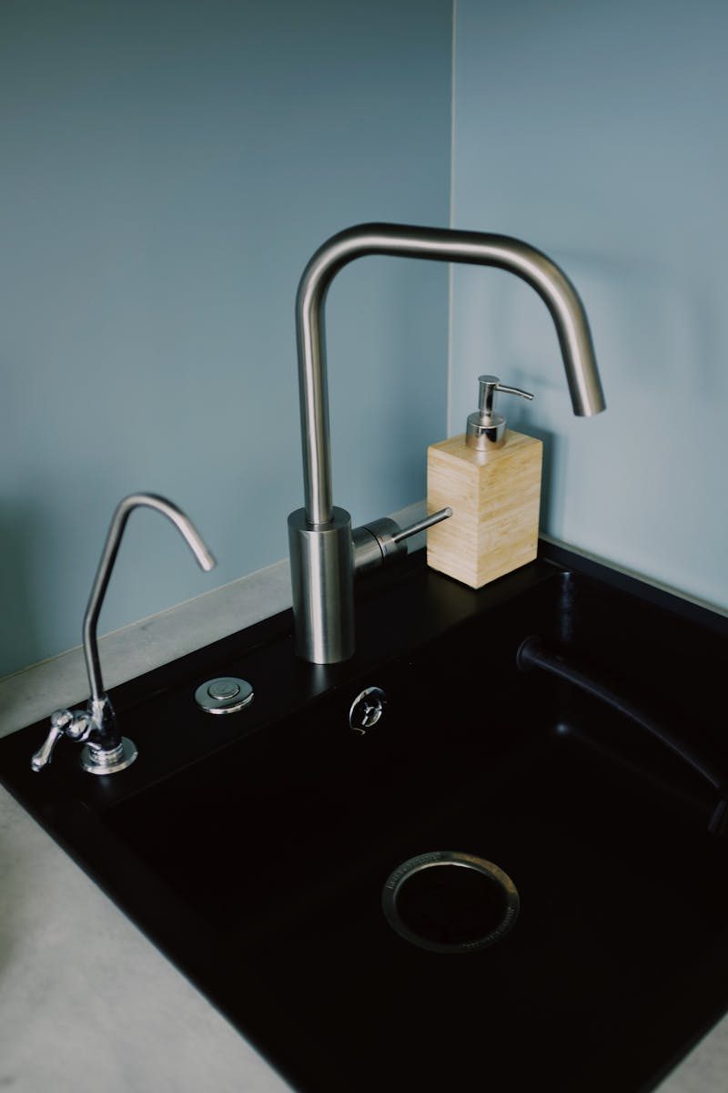 A sleek, modern kitchen sink with a stainless steel faucet and soap dispenser, perfect for contemporary interiors.